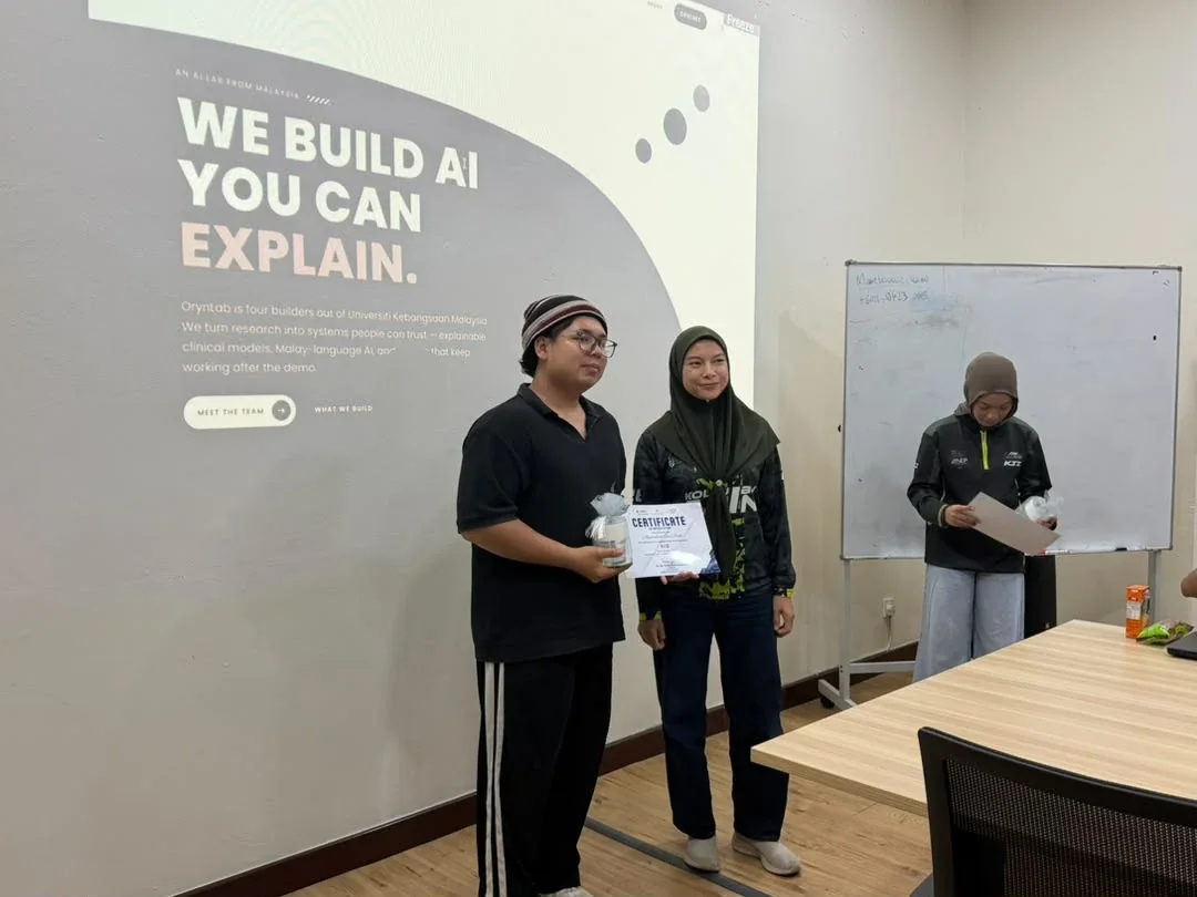 A certificate being presented in front of the OrynLab website on the projector